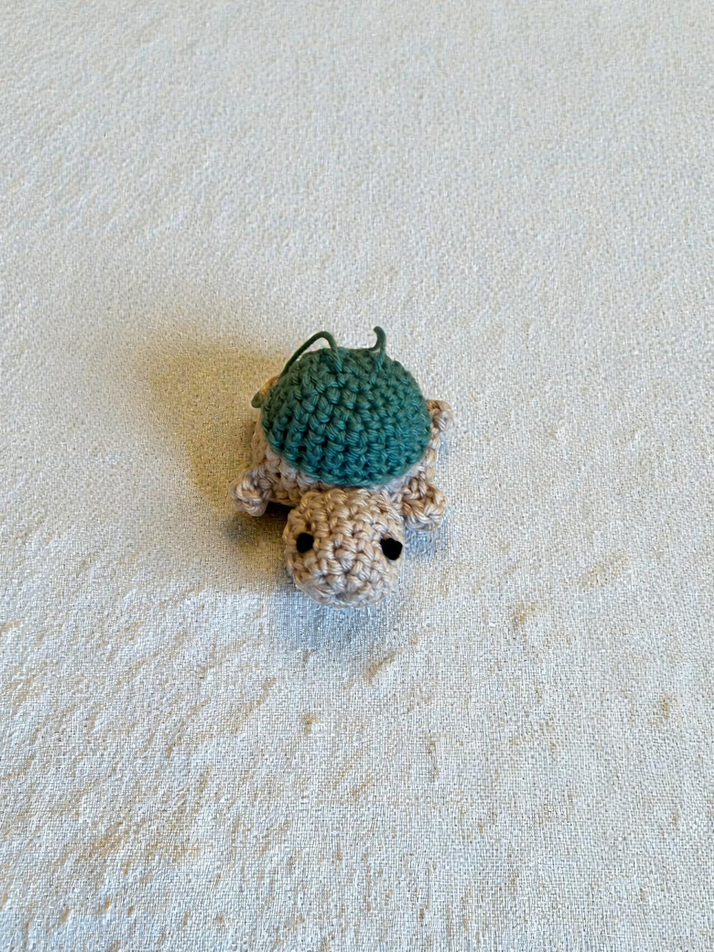 "TURTLE nøkkelring - heklet skilpadde i turkisgrønn og beige sett ovenfra"